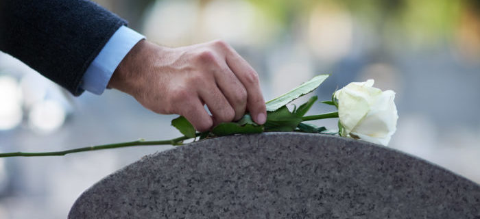 un hombre dejando una rosa blanca en una tumba